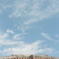 青空と赤瓦屋根の上のシーサーの写真