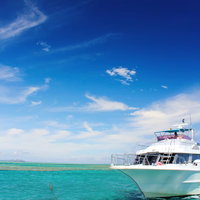 エメラルドグリーンの海に浮かぶ白い船の写真