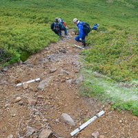 足場の悪い乗鞍新登山道の急斜面を下る登山者の写真