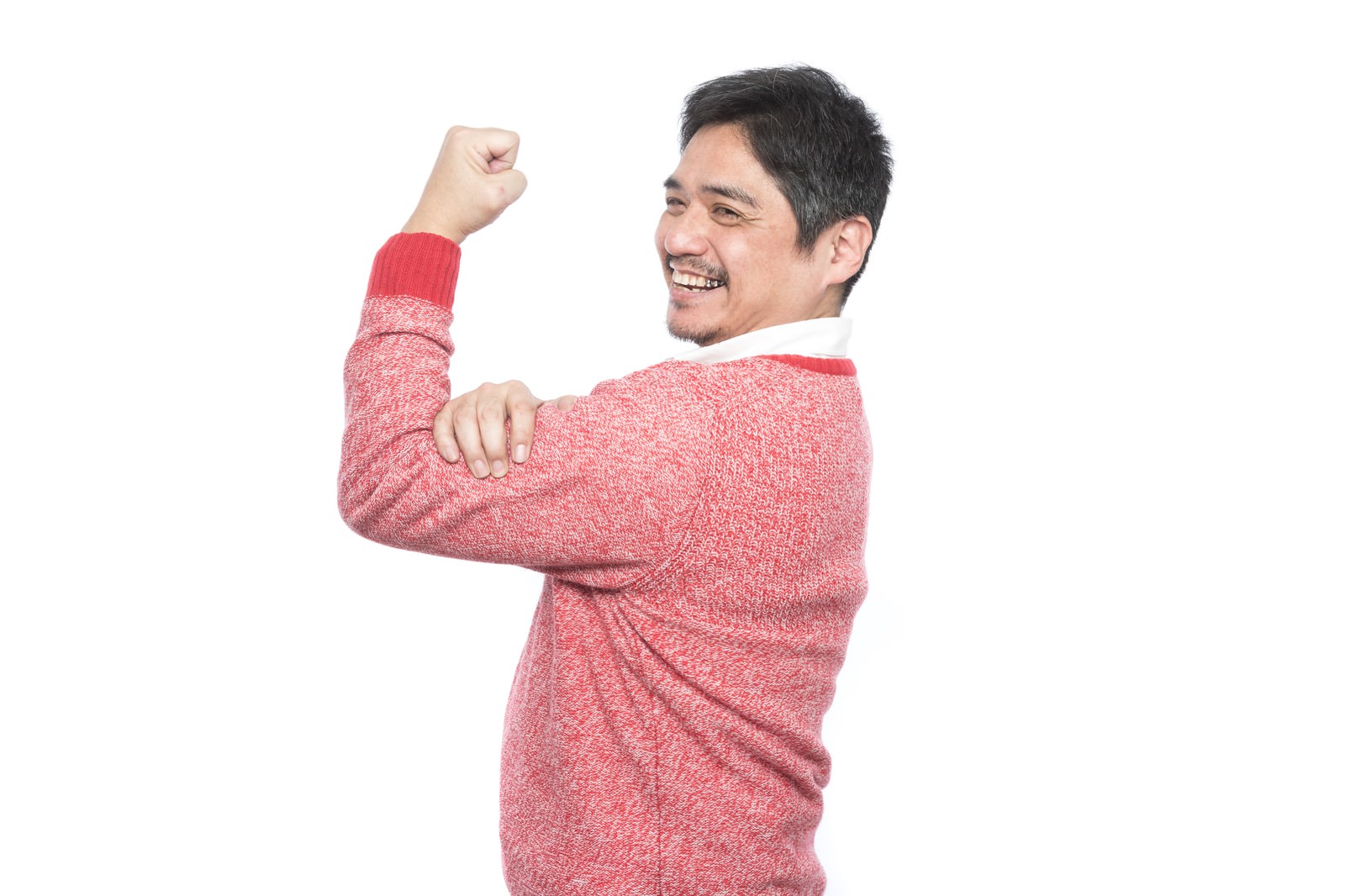 ピンクのニットを着た男性がガッツポーズで笑顔を見せている［モデル：よたか］