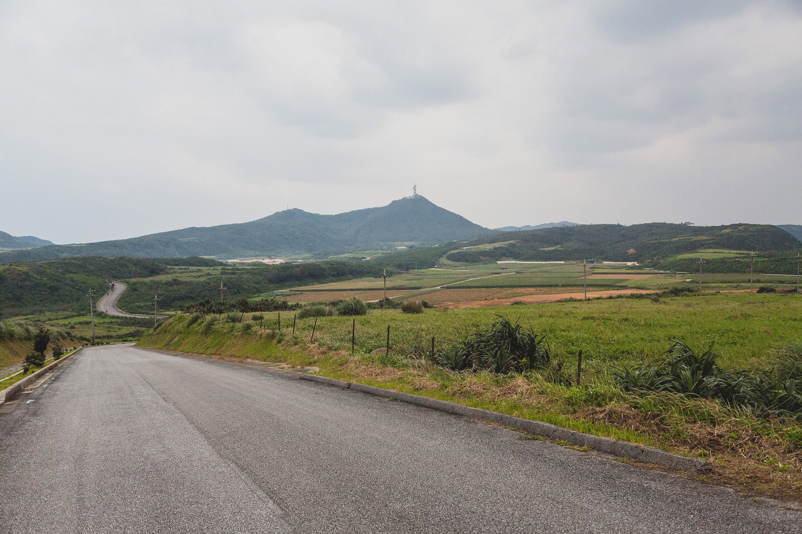 Scenic rural landscape with farmland and mountains under a cloudy sky on Yonaguni Island