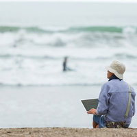 サーファーの同僚に海へ連れて行かれるも、まわりの雰囲気に溶け込めずノートパソコンでコーディングをはじめてしまうデザイナーの写真