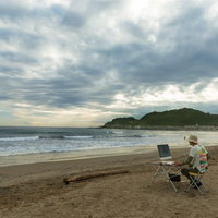 徹夜しすぎて浜辺でコーディングしているかの幻覚をみているWebデザイナーの写真