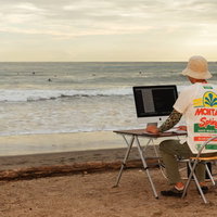 本当に浜辺でコーディングしているWebデザイナーの写真