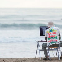 GW明け、締め切りの波が続々と海辺の浜辺に押し寄せるWebデザイナーの写真