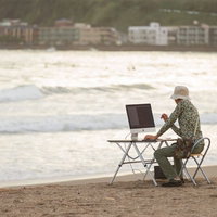 サーフィンをしに海へ来たのに、ついついコーディングしてしまうIT戦士の写真
