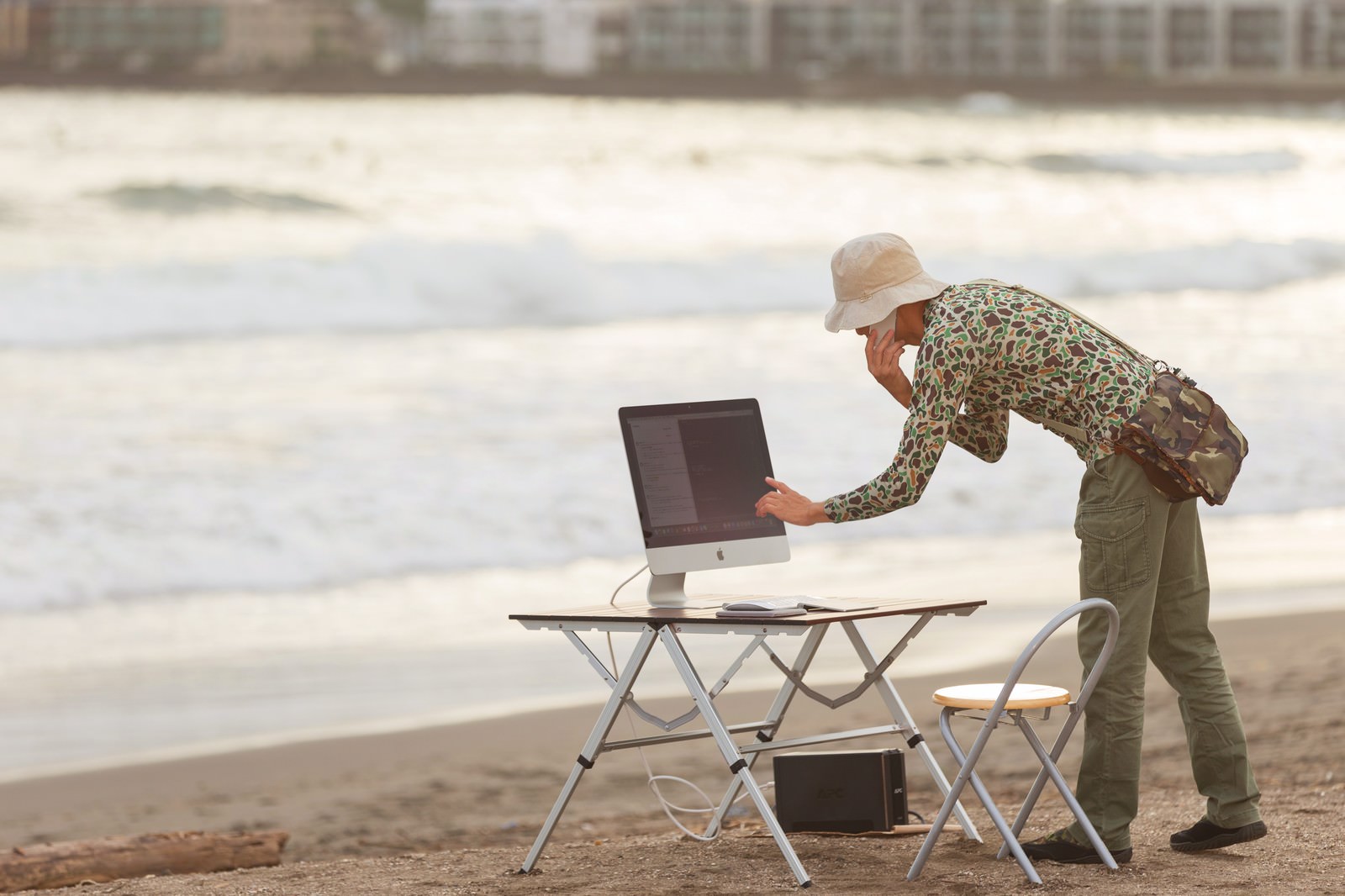 砂浜でデスクトップPCを操作する男性