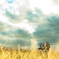 入稿前のデータが飛んで周りが草原になったデザイナーが帽子をかぶりパソコンで作業の写真