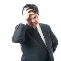 手形不渡りで頭を抱える中年男性経営者、経営危機に直面の写真