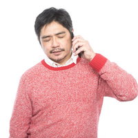 娘からの電話は大抵お金の話。赤いニット姿で通話する中年の上司の写真