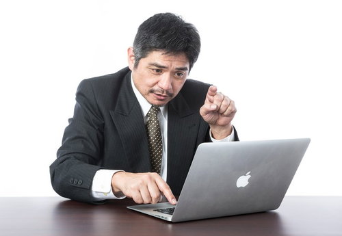 キーボードの一本指打法をする中年の上司