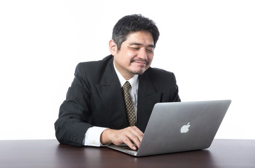 ノートパソコンを操作しながら微笑む中年の上司
