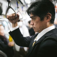 満員電車で通勤する中年男性会社員の疲れた表情の写真