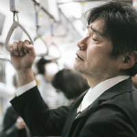 満員電車の通勤で疲れ切った中年男性（スーツ姿）の写真