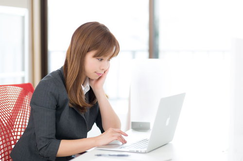 明るいオフィスでMBAのパソコンを操作する女性社員