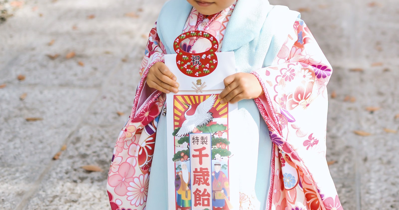 七五三の着物姿の子どもが千歳飴と巾着を手に持つ