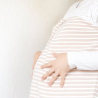 妊婦さんが触れるおなかの中の赤ちゃん、ボーダー柄のマタニティトップスの写真