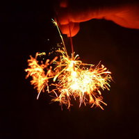 夜空の山並みを背景に光る線香花火の写真