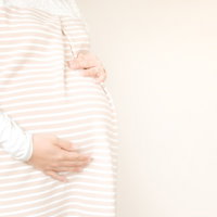 室内で胎動を感じる妊婦の母親の写真