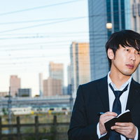 都市部でスマートフォンを見つめるジャーナリストの男性の写真