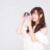 フィルムカメラで撮影する白トップスの女性の写真