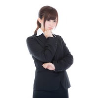 考えこむスーツ姿の女性社員、デスクで課題に悩む職場の思案シーンの写真