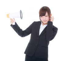 スピーカーの大声がうるさくて嫌になる女性社員の写真