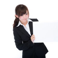 黒いスーツでフリップを持って説明する女性社員の写真