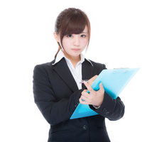 クリップボードでチェックシートを確認するビジネスウーマンの写真