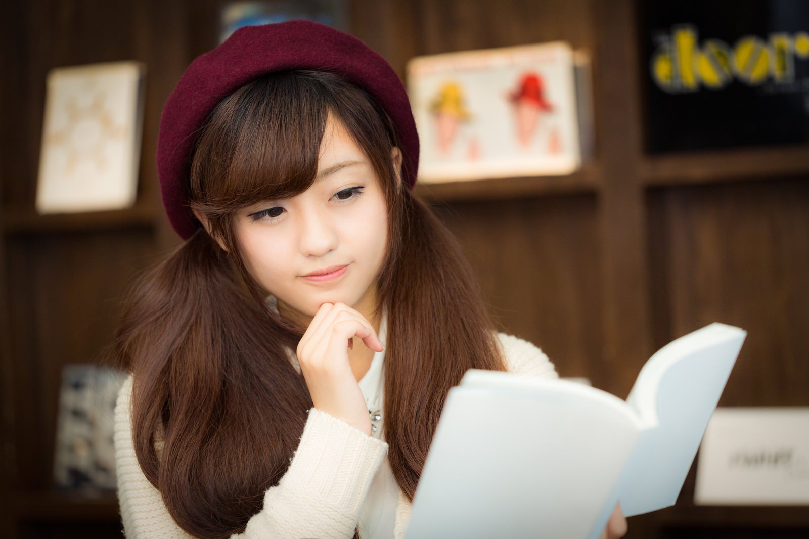 ベレー帽をかぶり、ノートパソコンを前に考えながら読書する女性［モデル：河村友歌］