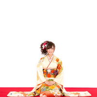 明けましておめでとうございます。赤と黄色の花飾りを髪に結んだ着物姿の女性の写真