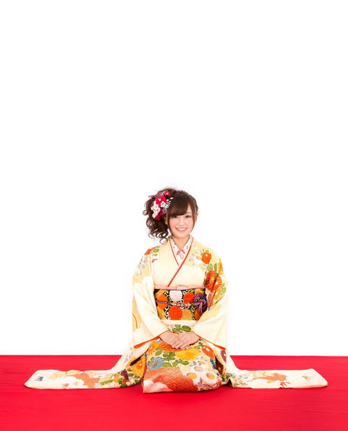 明けましておめでとうございます。赤と黄色の花飾りを髪に結んだ着物姿の女性