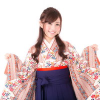 花柄の着物と紺色の袴で笑顔の女性、両腕を広げての写真