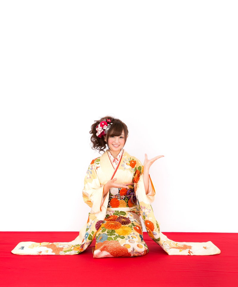 振袖姿の女性が右手を上げ新年のお知らせを示している［モデル：河村友歌］