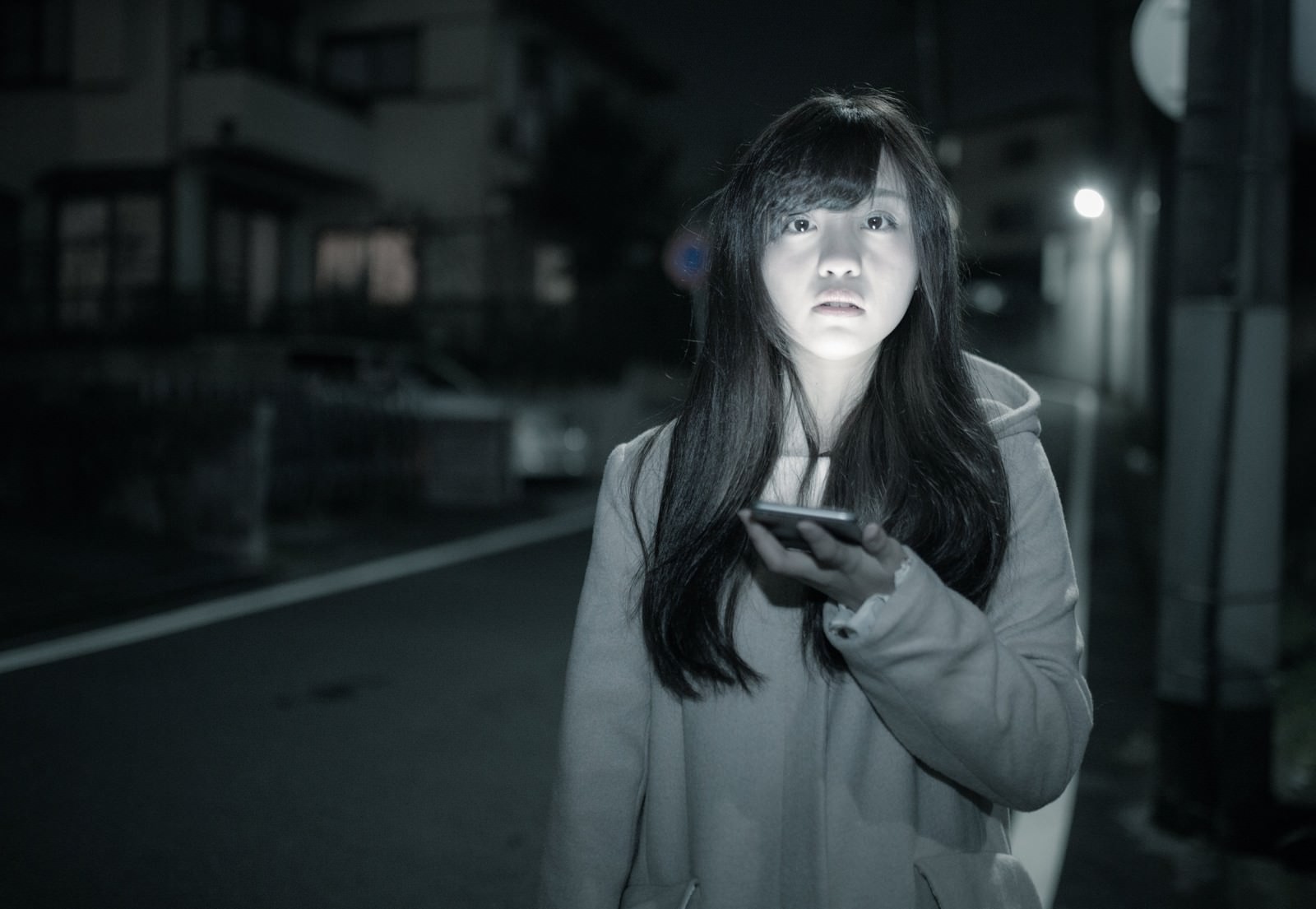 深夜の街でスマートフォンを持ちながら歩く長髪の女性［モデル：河村友歌］