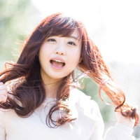 太陽光の中で髪をかき上げて笑うキラキラ女子の写真