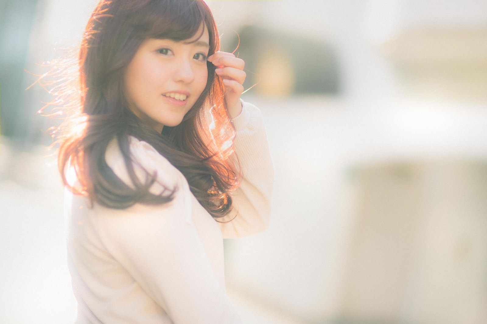 風で髪をなびかせながら振り返って笑う女性［モデル：河村友歌］