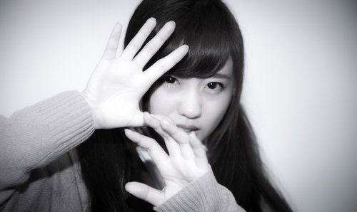 スクープを激写される女子高生が顔を手で覆う防御の仕草