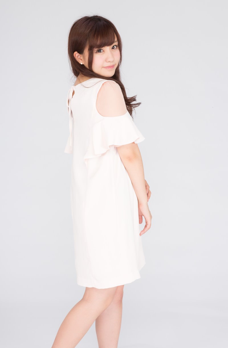 白いオフショルダーワンピースを着て振り返る女性［モデル：河村友歌］