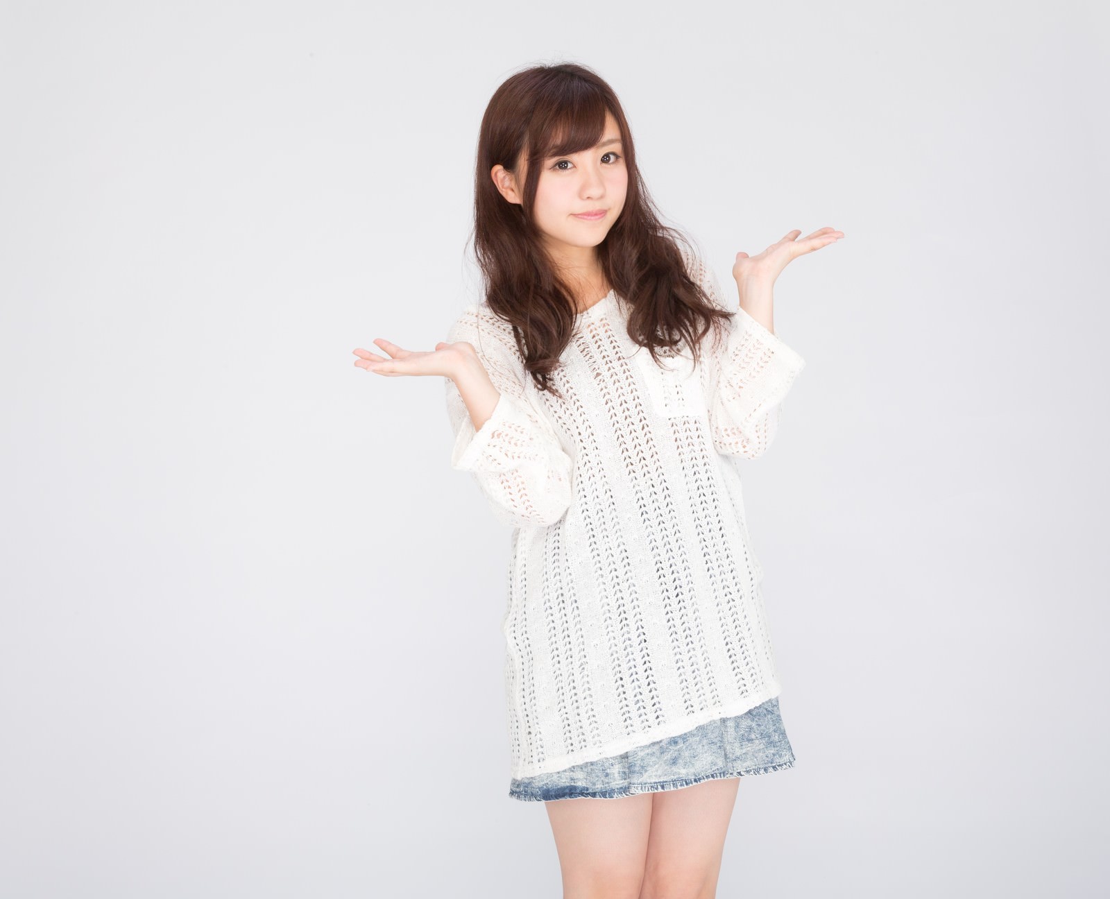 白いニットワンピースを着た女性が両手を広げて笑顔でポーズしている［モデル：河村友歌］