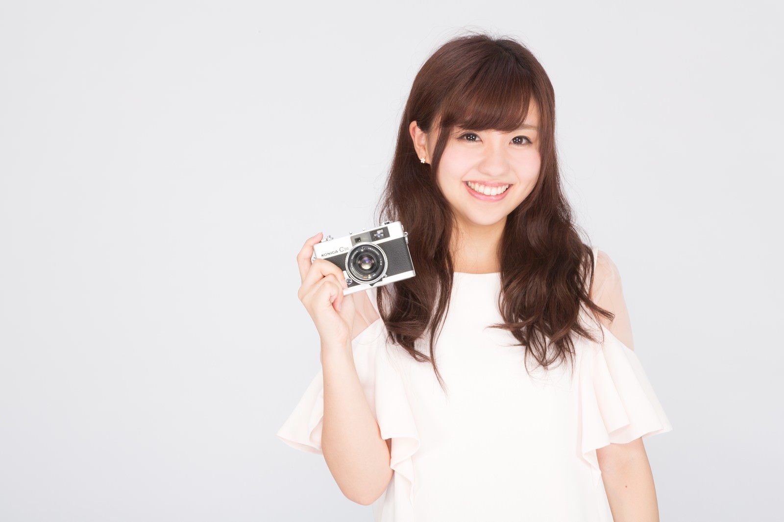 レトロカメラを持ち笑顔の女性［モデル：河村友歌］