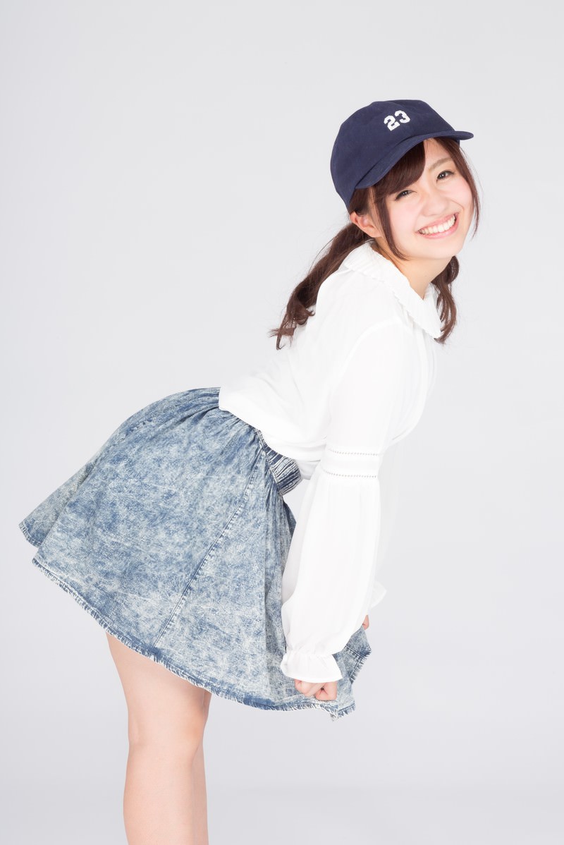 紺キャップと白トップス・デニムスカートで笑う女性［モデル：河村友歌］