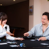 女性ディーラーと楽しくポーカーをプレイする男性の写真