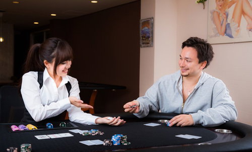 女性ディーラーと楽しくポーカーをプレイする男性