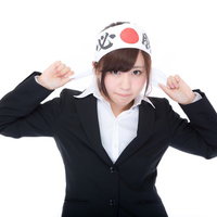 必勝ハチマキで気合を入れるスーツ姿の女性の写真