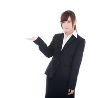 ご案内するスーツ姿の受付嬢が左手で指し示すの写真