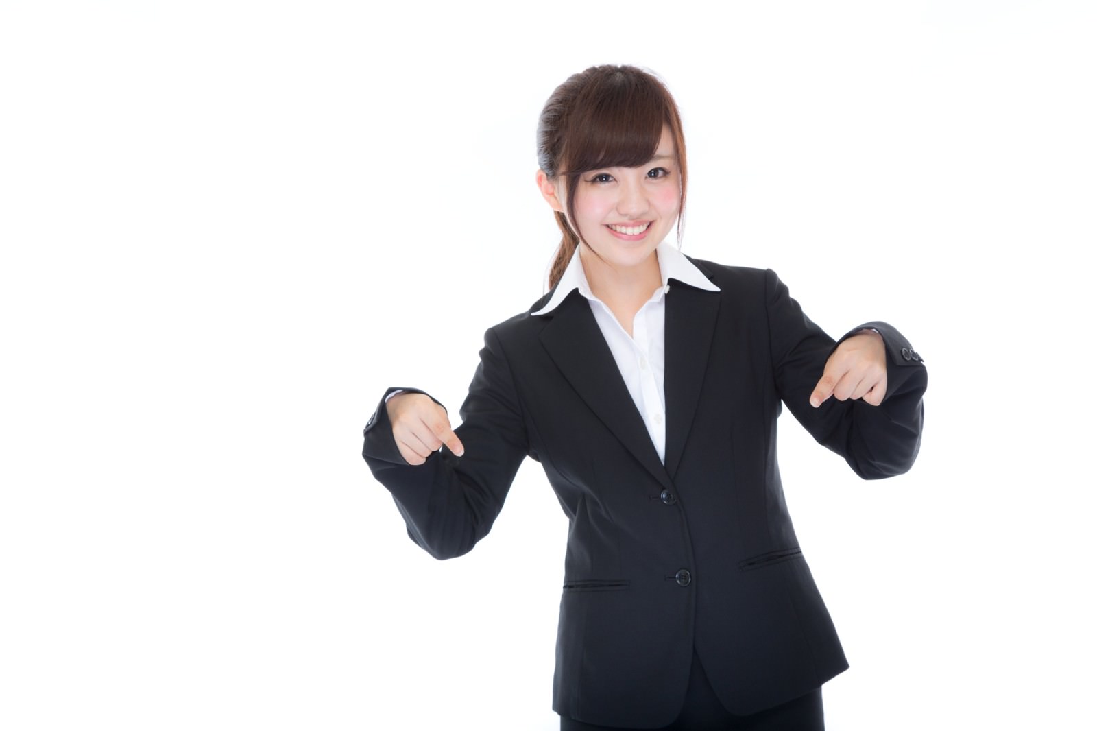 黒いスーツを着た女性が両手の人差し指で斜め下を指しながら笑顔で案内している［モデル：河村友歌］