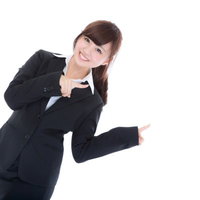 黒いスーツで両手で指をさす案内係の女性の写真