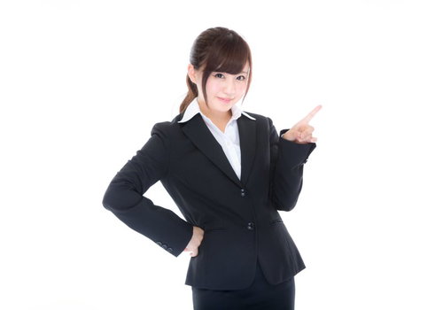 指をさしてご案内するスーツ姿の受付女性のおもてなしの様子