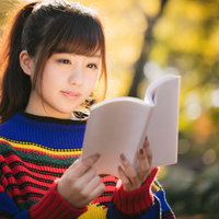 紅葉の秋とマルチカラーな読書着で本を読む女子の写真